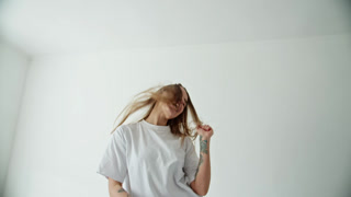 Tattooed woman happily dancing and singing with her phone on a white background