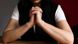 Woman praying with hope holding hands clasped together, lady praying God, asking for help or waiting for miracle alone.
