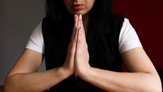 Woman praying with hope holding hands clasped together, lady praying God, asking for help or waiting for miracle alone.