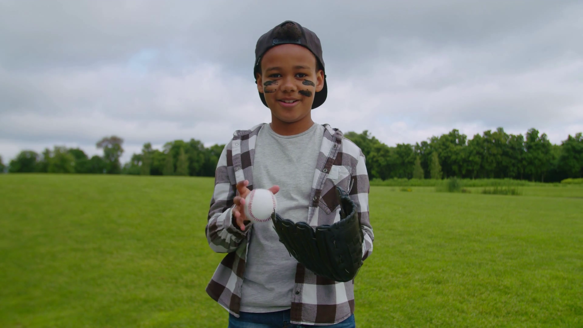 Portrait of cute preadolescent boy pitcher wearing eye black and baseball cap, throwing baseball