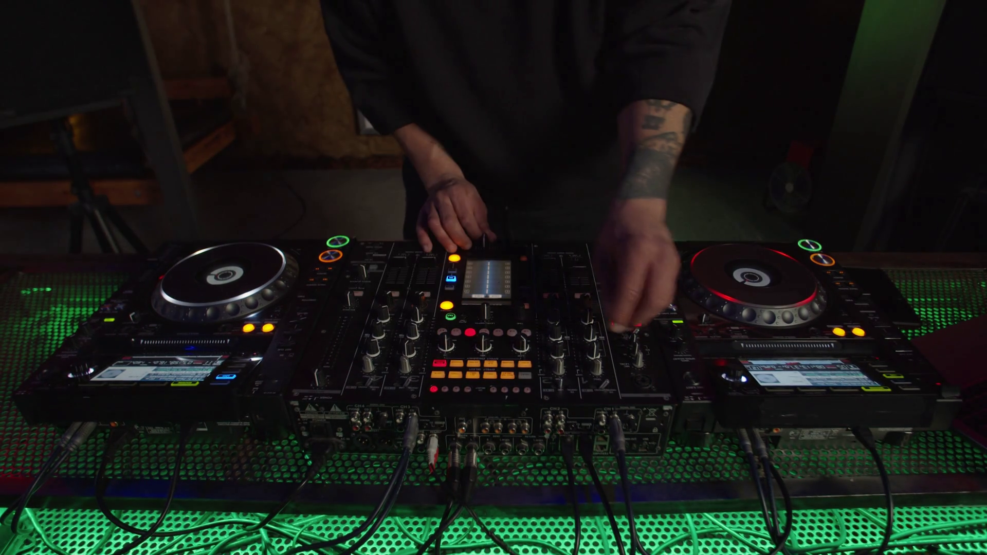 Closeup of DJ hands mixing track on sound mixer station and turntable