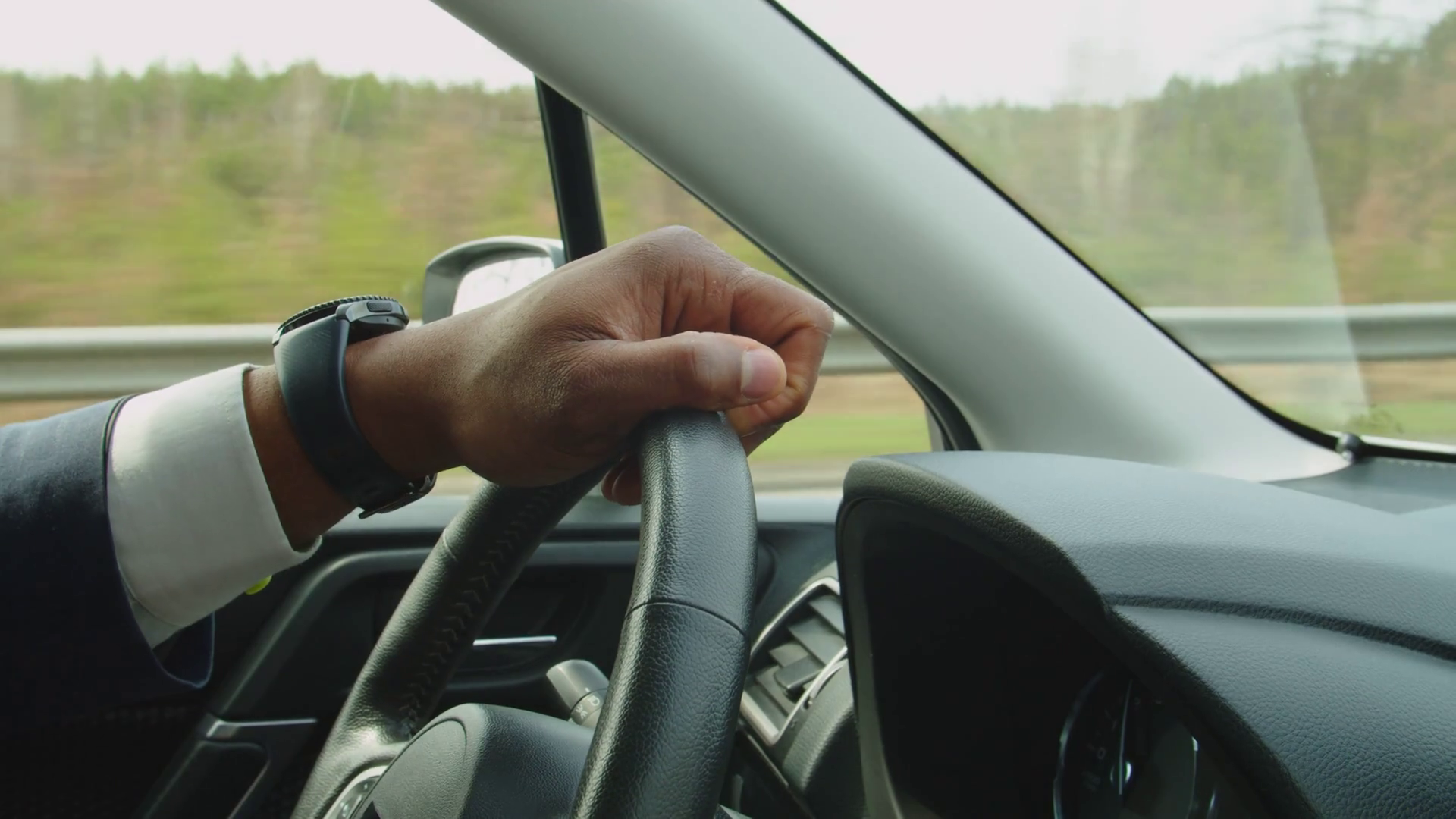 Side view of hand of black male driver firmly holding steering wheel