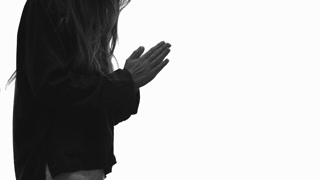 Woman, prays with clasped hands for help, standing on white background.