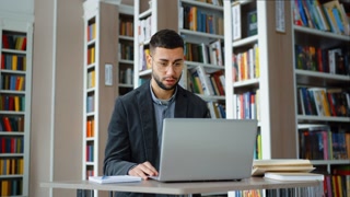 Virtual Meeting: Young Man in Library Engaged in Online Education