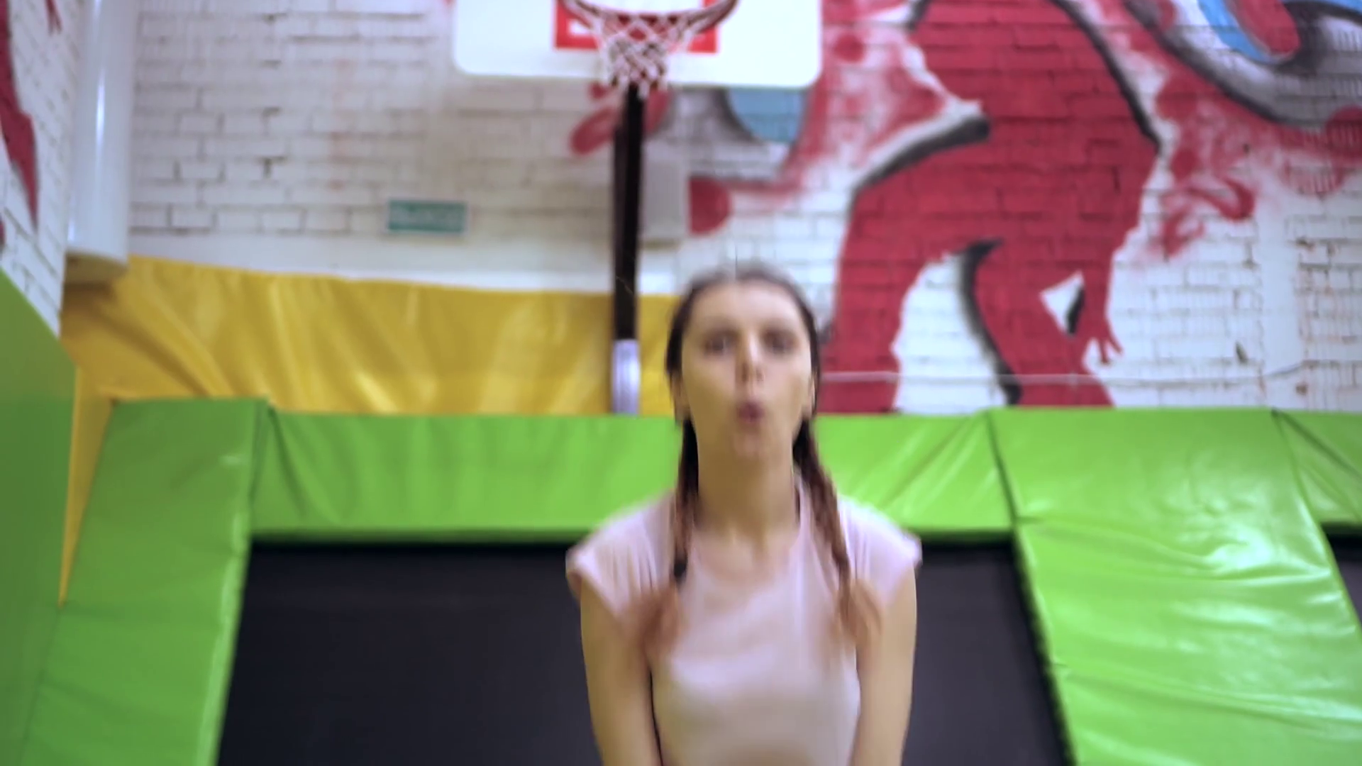 A young girl throws the ball from behind and falls into the basketball