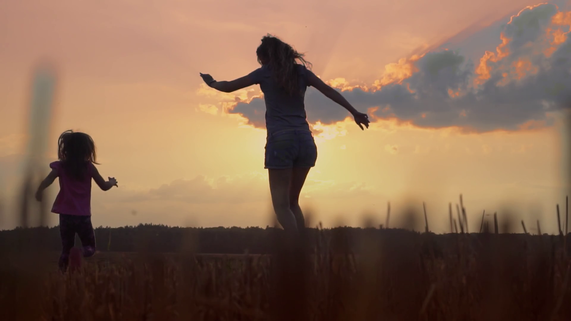 Mom runs with the daughter on the sunset, throws up and spins the happy