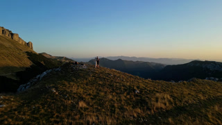 Couple standing on a mountainside at Col de la Bataille, Ombleze, Vercors, France during sunset.