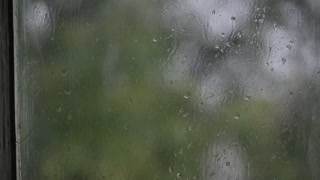 Close-up of water droplets on glass. Large rain drops strike a window pane during a summer shower. 4K.