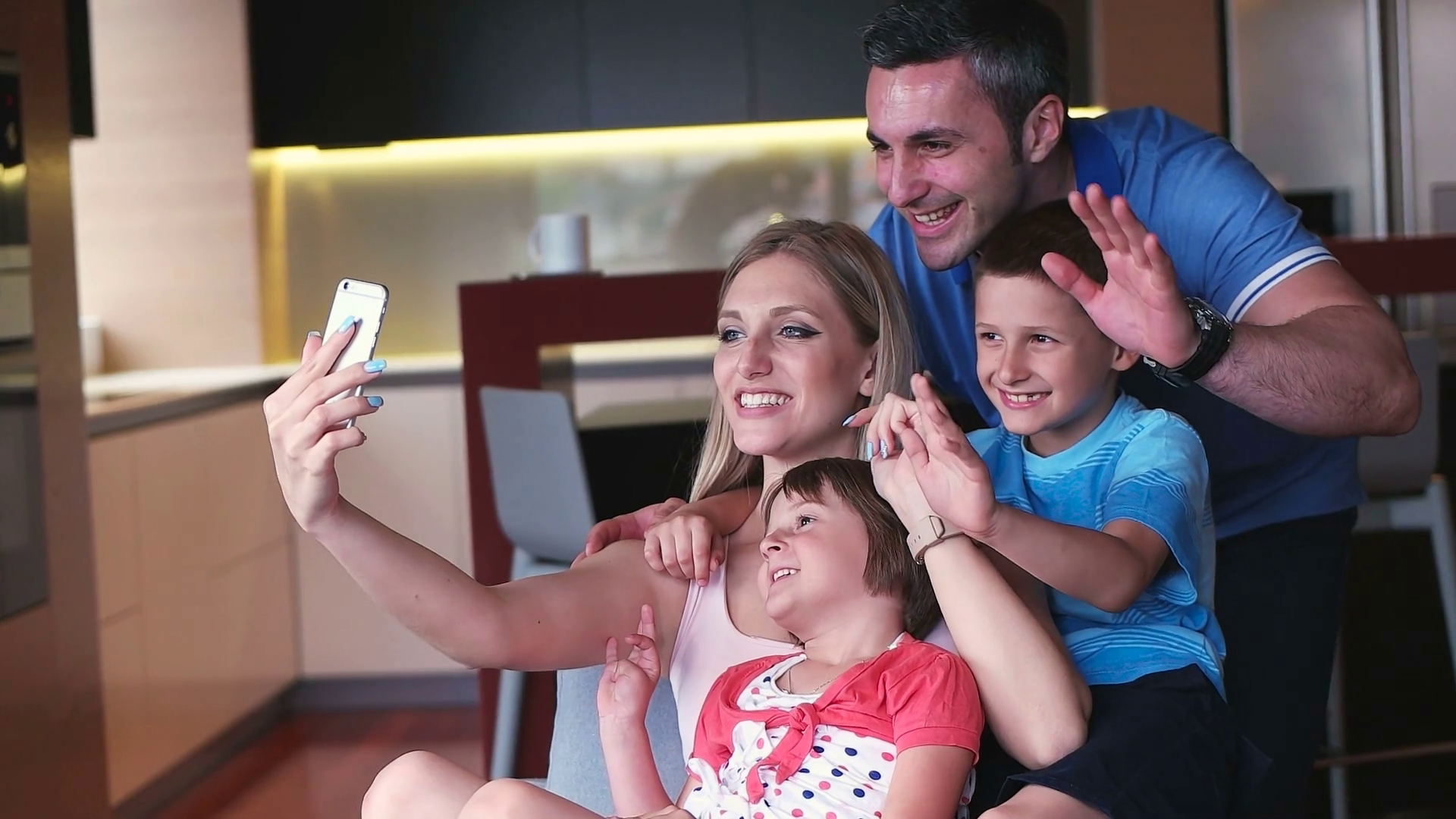 Happy family siting on sofa and using cell phone for video call at home