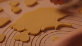 Young woman bakes and decorates heart shaped cookies with icing and sprinkles for valentines day