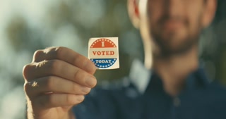 Young man smiling with an I Voted sticker and pin 
