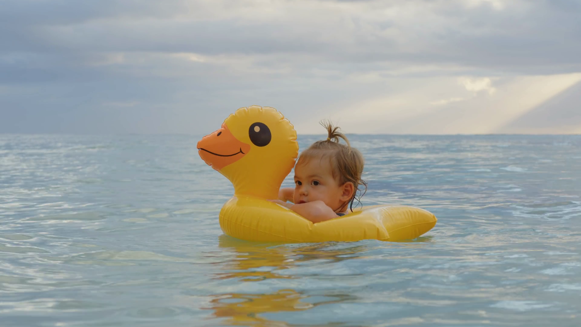 Portrait of little adorable baby floating on an inflatable duck in the