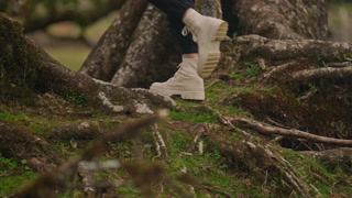A traveler in a yellow jacket, hat and backpack walks on a paradise island. Active young woman climbs on top of cliff for a view in hiking