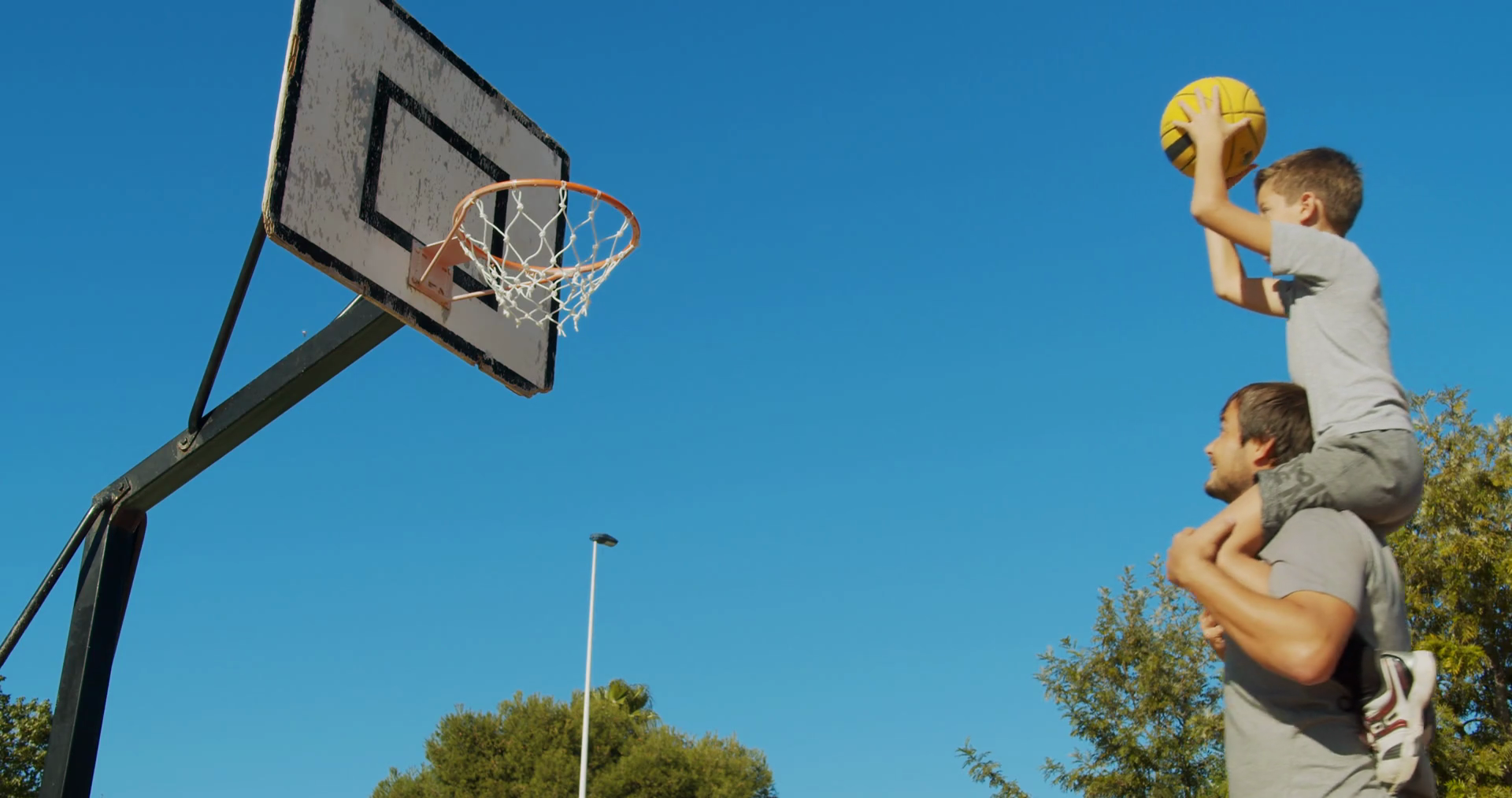 Father and son playing basketball on the street and throwing a ball to