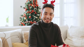 African American man enjoys Christmas celebration with holiday decorations and gift exchange near a Christmas tree during New Year