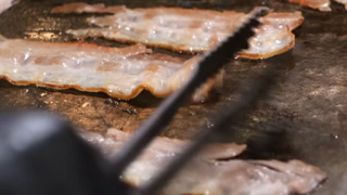 Macro Close-up of Crispy Bacon Strips Sizzling on a Professional Restaurant Grill