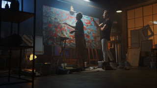 In the Art Class: Talented Young Woman Artist Paints with a Brush on the Large Canvas, Her Prominent Mentor Painter Teaches Her about Technique and Styles