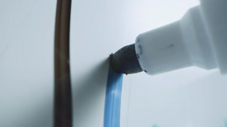 Macro Follow Shot of a Blue Marker Pen Being Held with a Hand. Person Writing