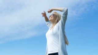 Beautiful Young Woman with Long Blonde Hair Happily Raises Her Arms to The Sun  Celebration Her Success in Life. Sun is Shining and Sky is Blue.