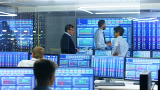 Three Experienced Stock Traders Talking Business, Consulting Documents and Argue About Data. They Work for a Big Stock Exchange Firm. Office is Full of Displays Showing Infographics and Numbers.