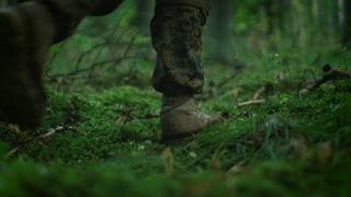 Close-up Fully Equipped Soldier's Boot Stepping on the Moss, Man Moves Further in the Dense Forest. He's on the Reconnaisance Military Mission. Low Angle Footage.
