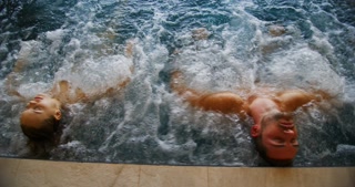 The young couples are enjoying and having relax in a whirl pool bath tube in a luxury wellness cen