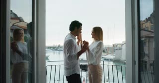 A cheerful young couple is enjoying time together on a terrace of a hotel room during their romant