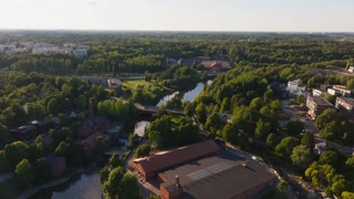 Sunlight illuminates buildings along a and creates a picturesque scene in Helsinki, Finland. A lush green landscape enhances the beauty of