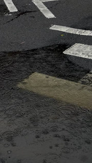 Raindrops on a Puddle: A Close-Up View of Rainfall in an Urban Setting