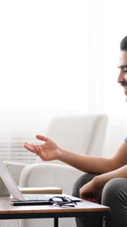 Adult man on laptop video call at home, side view