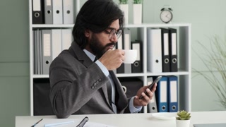 Indian businessman enjoying coffee break and browsing phone