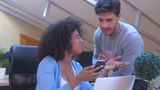 Man and woman sharing media content on mobile phone at office
