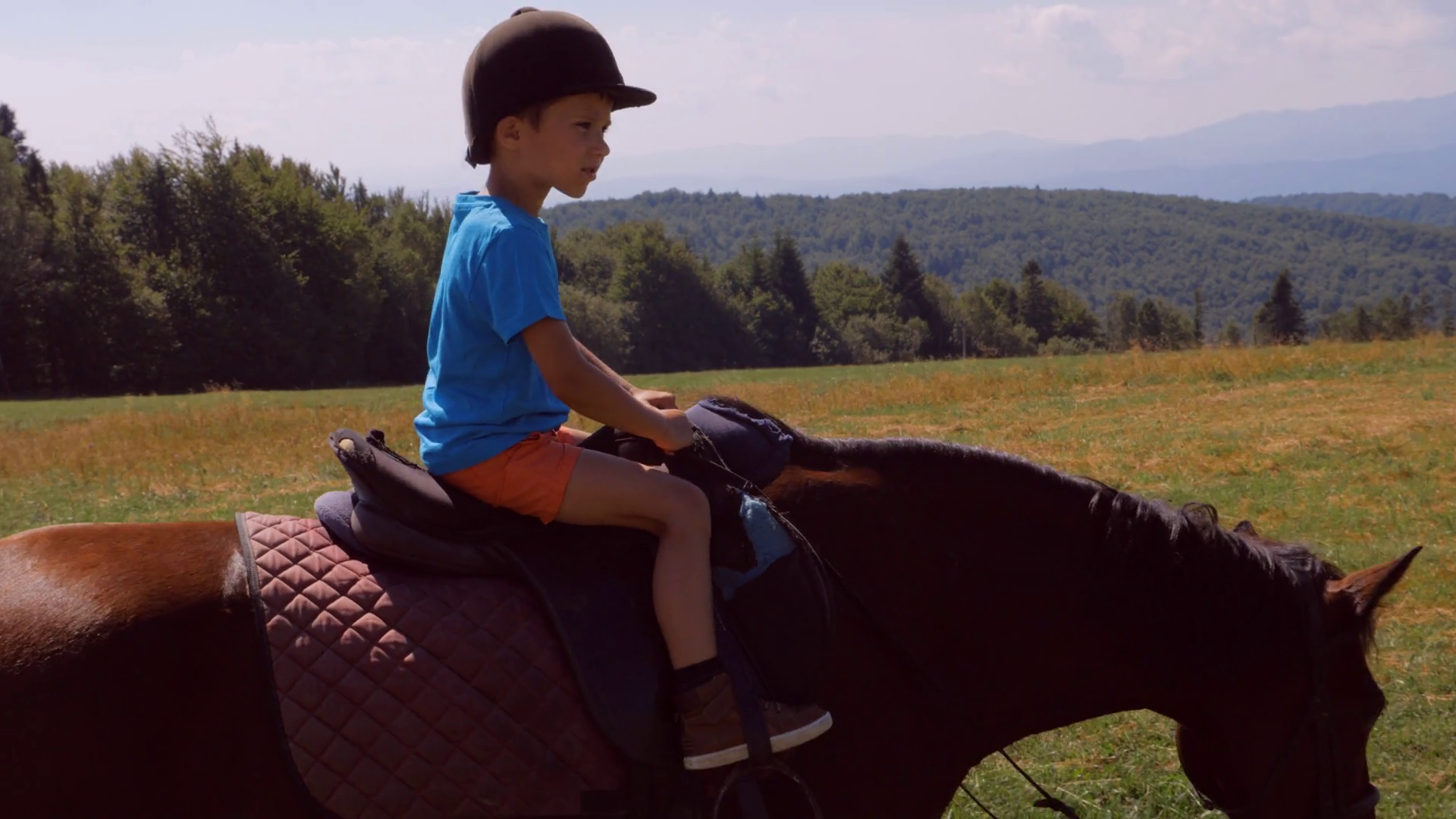 Small boy riding a horse in mountains