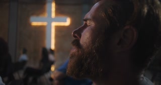 Man praying in church with eyes closed, bearded, emotional engagement, worship, spiritual moment, Christian faith, community