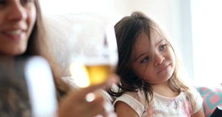 Mom Holding Beer Glass, While Little Girl In The Background Looking