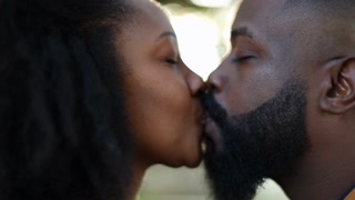 African Couple Kissing Each Other Outside In Sunlight Flare