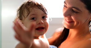 Mother Holding Baby After Shower Cute Toddler Blinking To Camera Infant Waving Hello Or Goodbye With Hand
