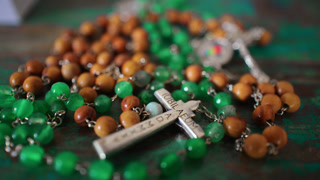 Catholic Rosary With Green and Wooden Beads and Silver Crucifix on Rustic Surface Representing Faith, Prayer, Devotion and Spiritual Reflection