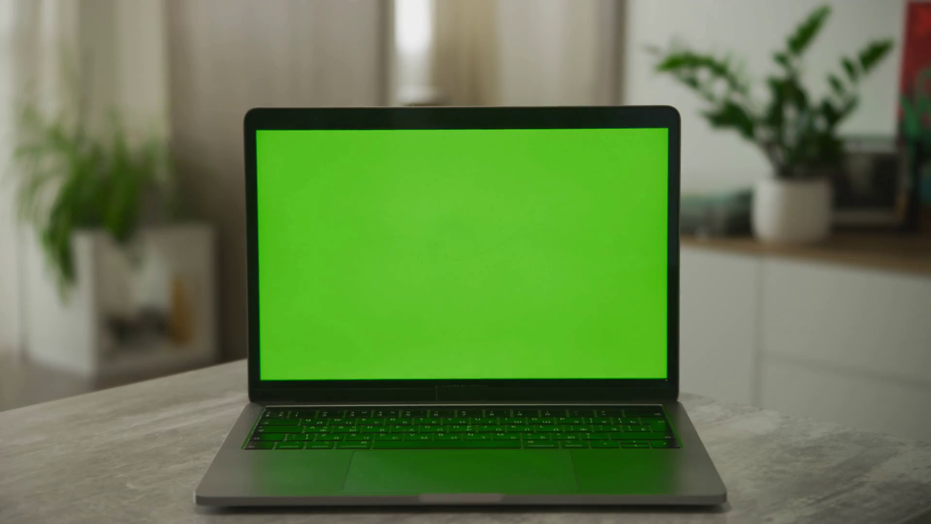 Static shot of a laptop with a green screen on a desk in modern