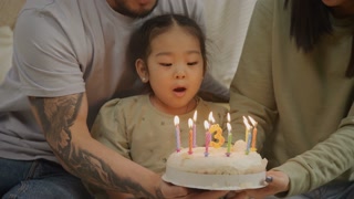 Baby girl blowing a candle on a birthday cake celebrating 3 years