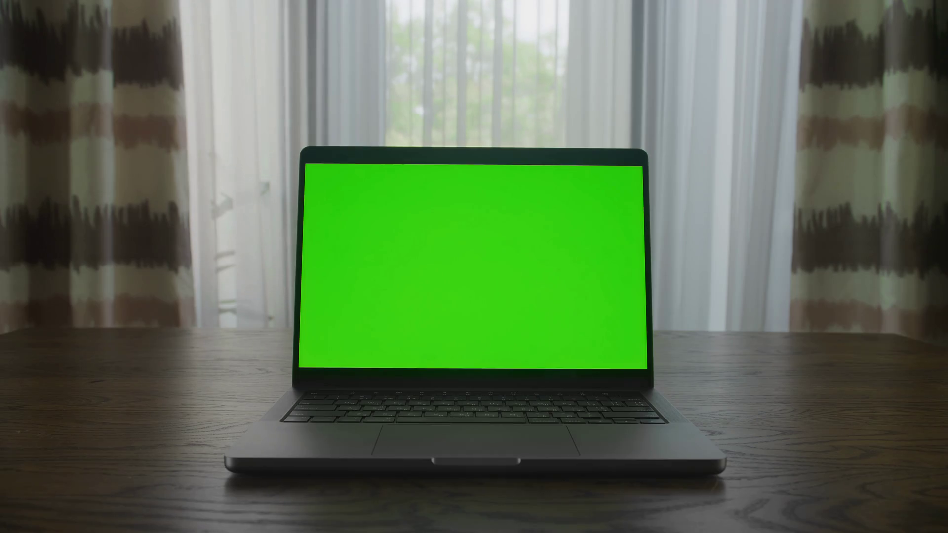 Slow optical zoom in into a laptop computer with green screen chroma