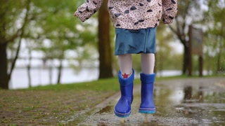 A joyful child splashes in colorful puddles, wearing bright rain boots and embracing the delight of rainy days