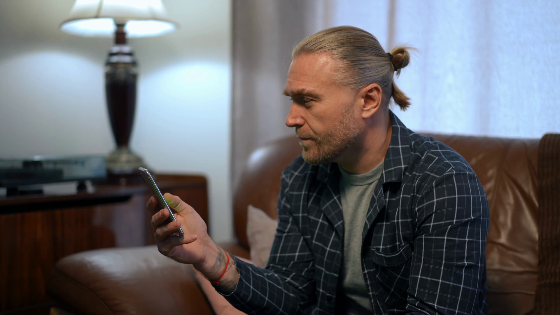 Amazed man showing green screen smartphone looking at camera sitting on