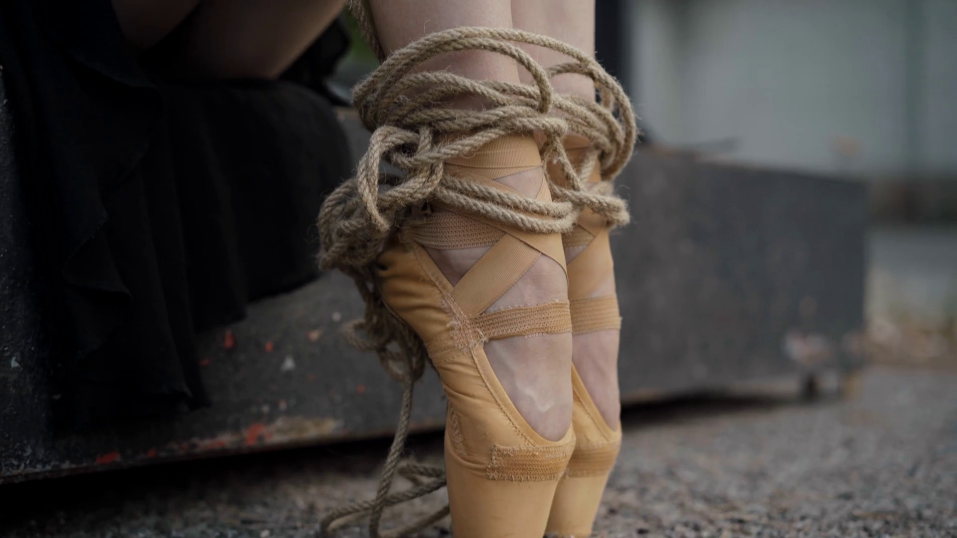 Camera moves up along legs of slim ballerina with legs tied with ropes