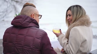 Back view romantic Caucasian adult couple toasting clinking champagne glasses smiling sitting outdoors. Happy confident man and woman dating on Valentine's Day on terrace.