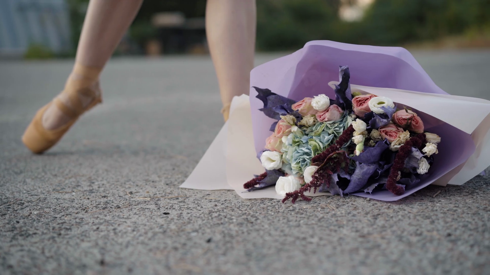 Close-up of flower lying on asphalt as slim ballerina in yellow pointes ...