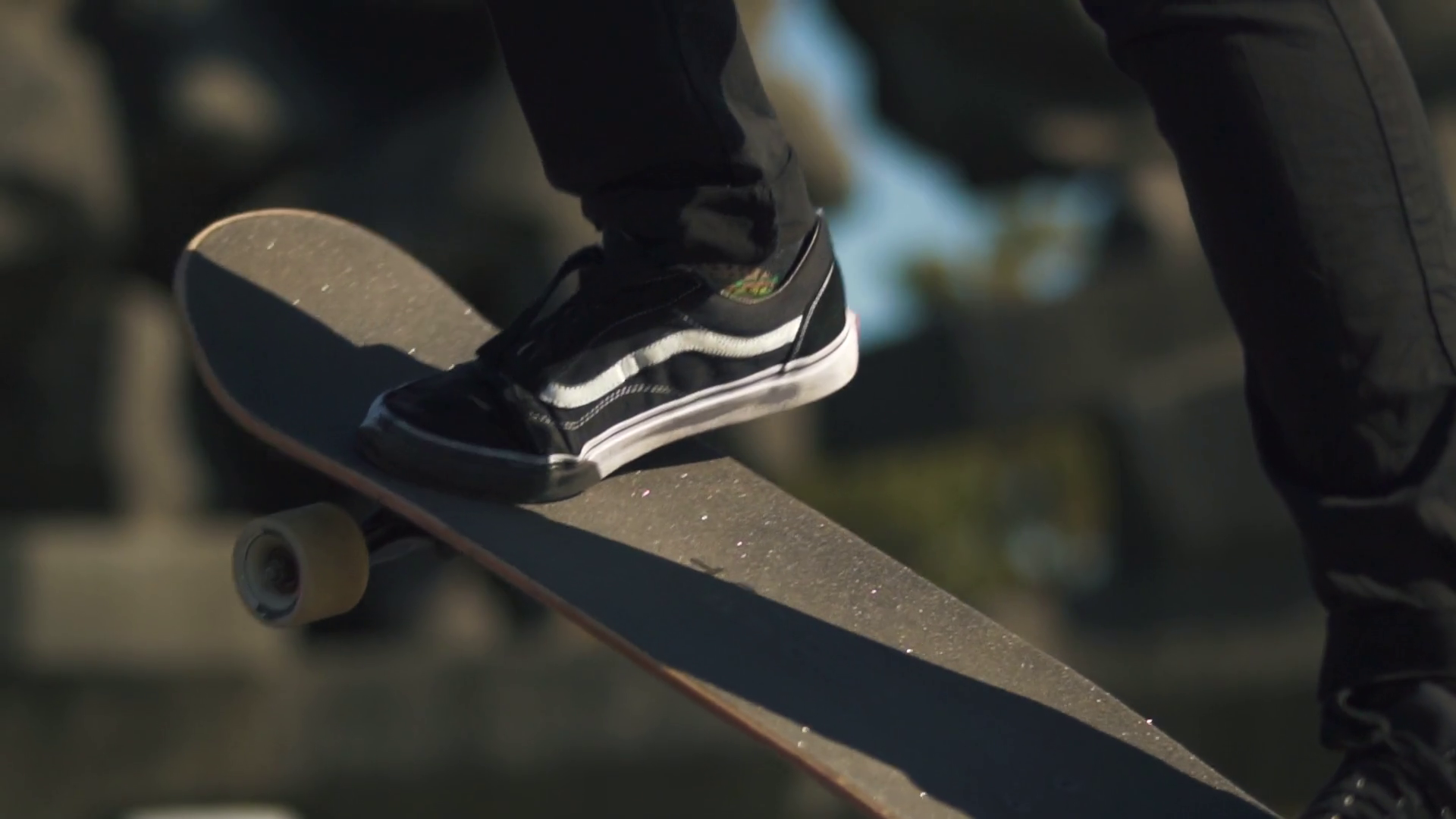 Closeup of legs in sneakers standing on a skateboard outdoors. Riding
