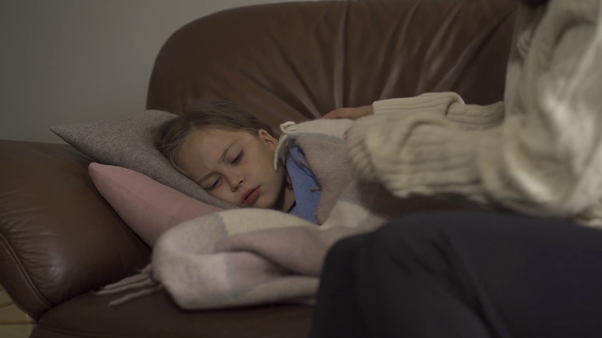 Closeup of sick caucasian girl lying under blanket at home. Sad child