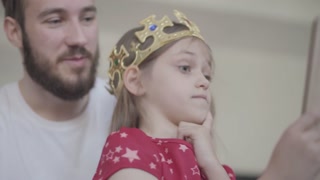 Loving father crowning his daughter, making her feel special. Family bonding and care.