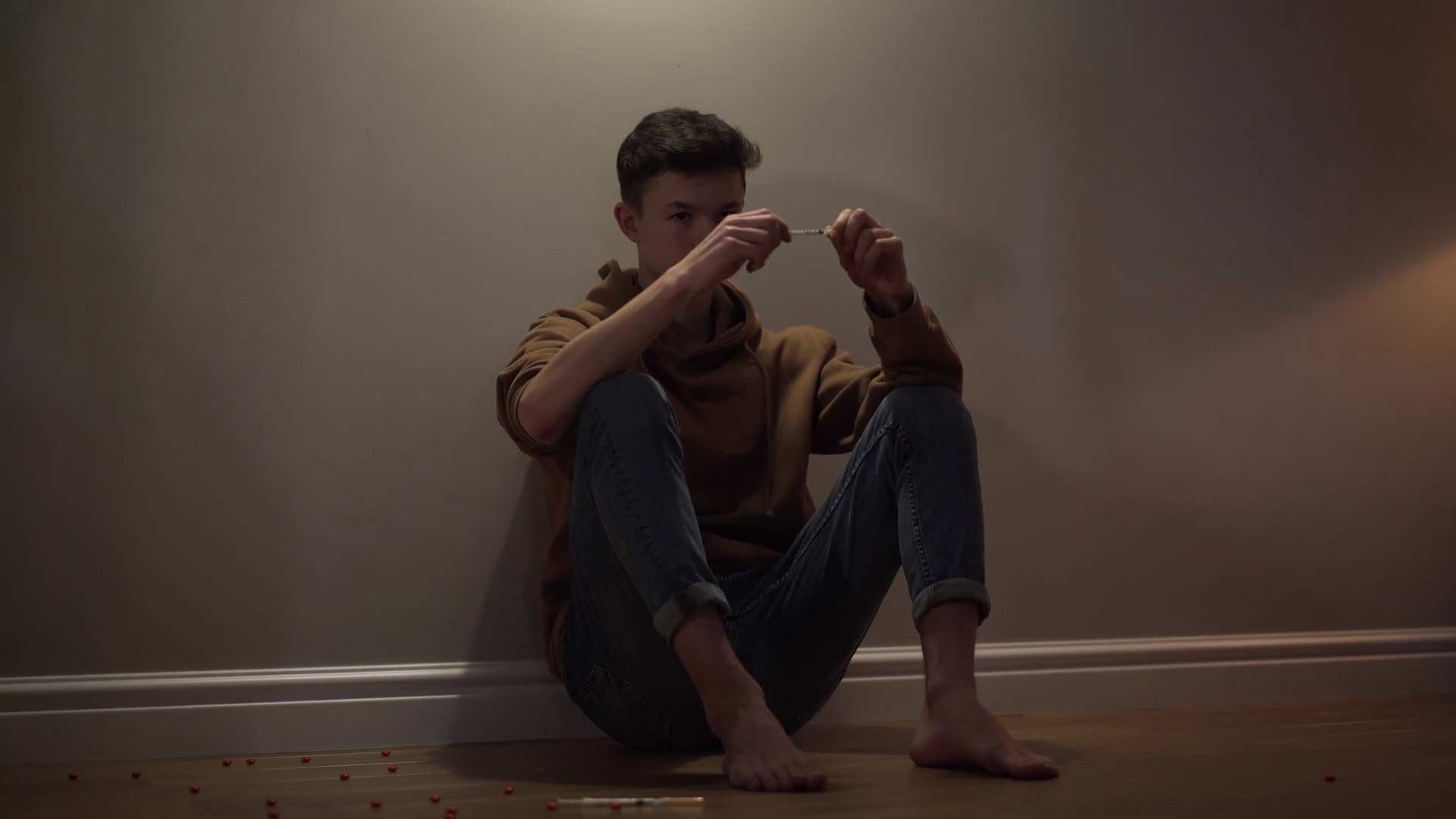 Portrait of addicted Caucasian boy sitting on the floor with syringe ...
